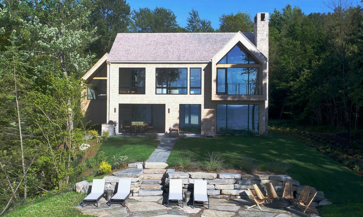 Lake house with stone terrace and lounge chairs