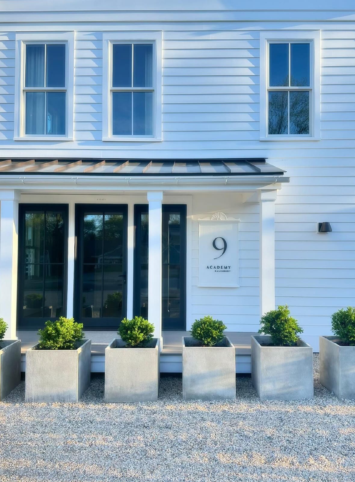 White clapboard entrance with planters