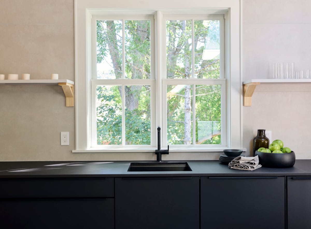 Black kitchen below a double window