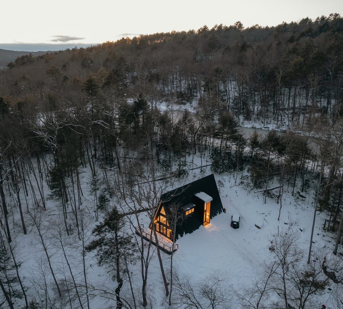 Aerial view of the A-frame cabin in snowy woods